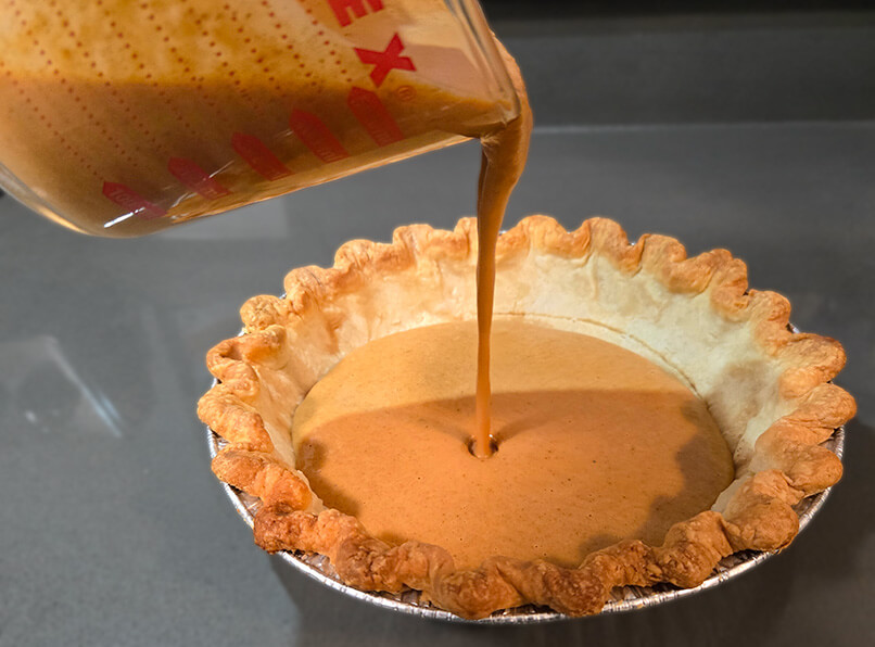 pouring pumpkin pie filling into a pie shell