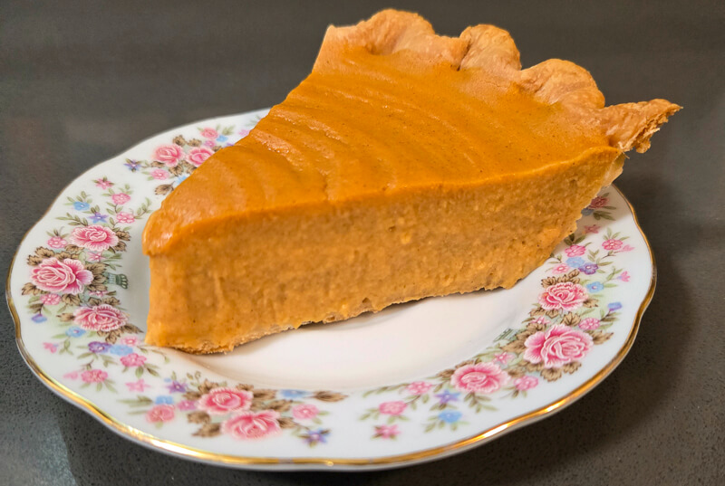 close up photograph of a slice of brown butter sweet potato pie in a flaky pie crust
