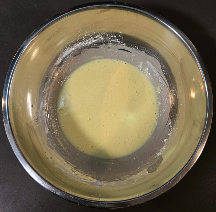 a photo of a mixing bowl with egg yolks, heavy cream, cornstarch, and salt mixed together before tempering the egg yolks