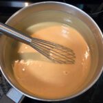 a photo of a pot with a whisk and butterscotch custard after cooking