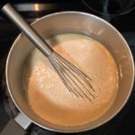 butterscotch custard before it thickens. The photo is of a pot with custard and a whisk