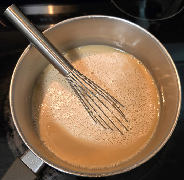 butterscotch custard before it thickens. The photo is of a pot with custard and a whisk
