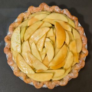 a pie shell with unbaked caramel apple pie filling inside and the edges of the pie crust creamed, almost ready to go in the oven