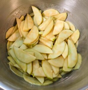 sliced apples being mixed for apple pie filling