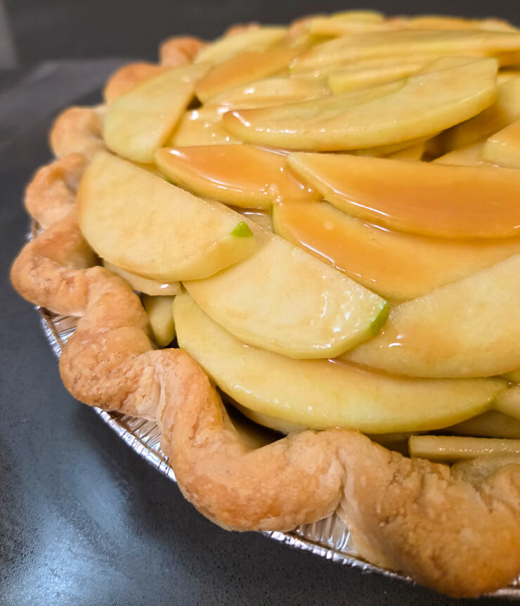 close up shot of apples in a pie shell with salted caramel sauce