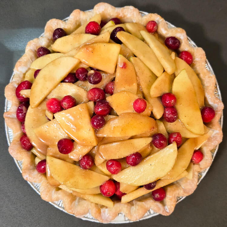 an untopped cranberry apple pie with the pie shell brushed with cream