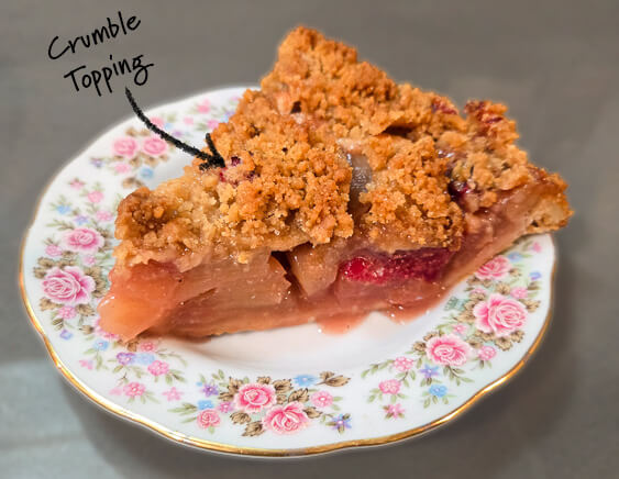 slice of cranberry apple pie on a decorative plate with a label that says "crumble topping