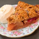 a slice of cranberry apple pie with a scoop of ice cream on a decorative plate
