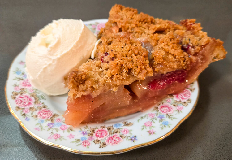 a slice of cranberry apple pie with a scoop of ice cream on a decorative plate