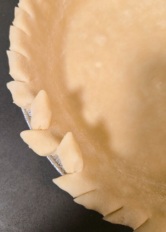 make a pie crust design by cutting a rolled edge to create a wheat stalk