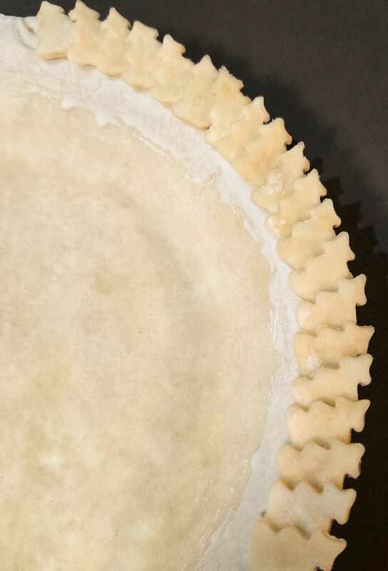 using cookie cutter cutouts of pie dough to decorate the edge of a pie crust