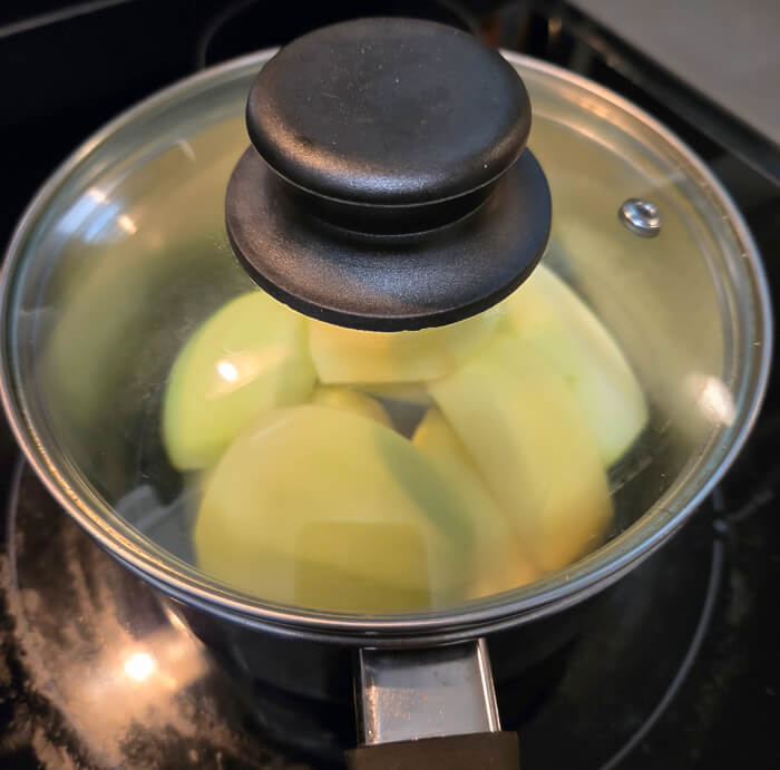 a photo showing the process of stewing apples in a pot on a stovetop