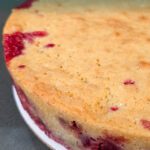 Side view of a golden cranberry cake showing layers of red cranberries at the bottom and tan almond batter on top, text overlay “Nantucket Cranberry Pie – Easy Holiday Upside-Down Cake Recipe.”