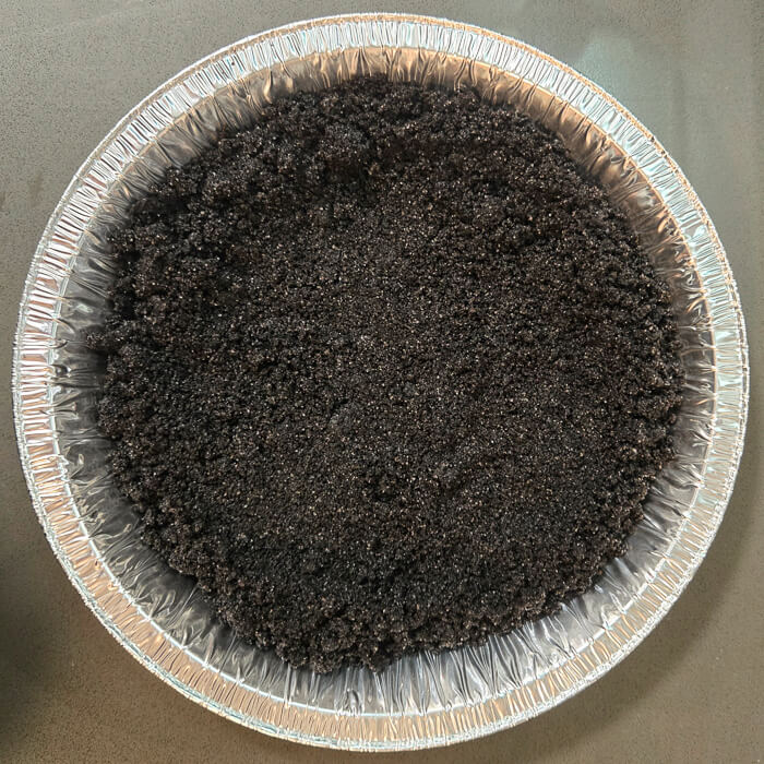 beginning to press an Oreo pie crust into a pie tin