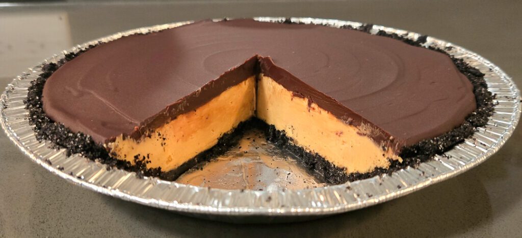 cross section of a no-bake peanut butter pie in an oreo pie crust with a chocolate ganache topping