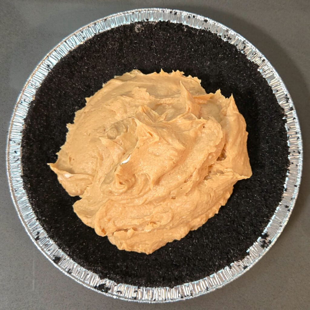 filling an oreo pie crust with a no-bake peanut butter cheesecake filling