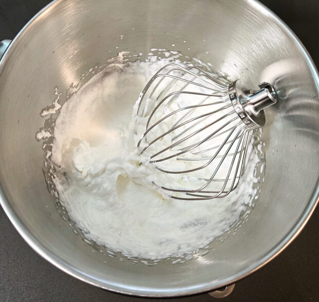 a photo of a mixing bowl with a whisk and freshly whipped cream
