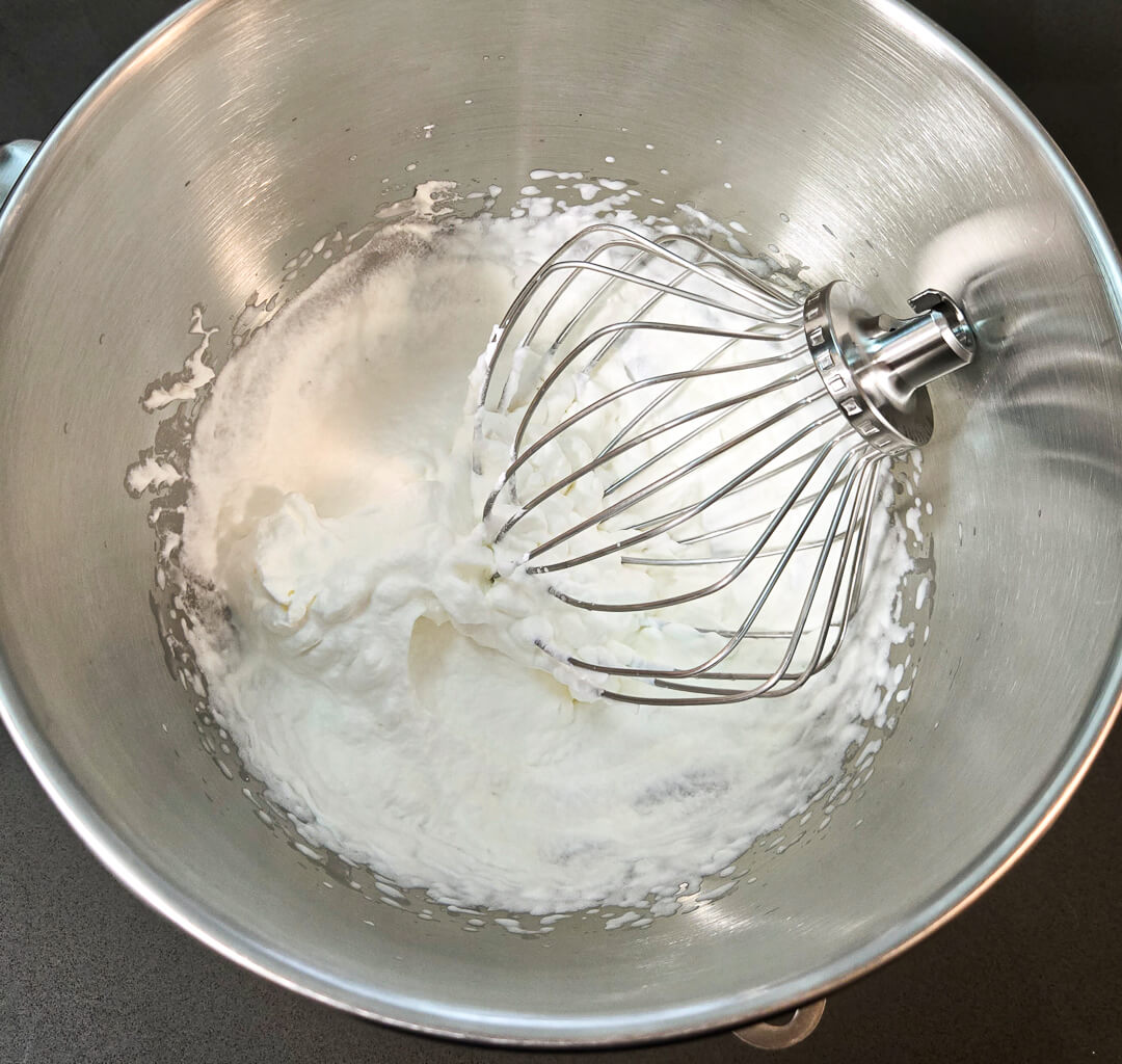 a photo of a mixing bowl with a whisk and freshly whipped cream
