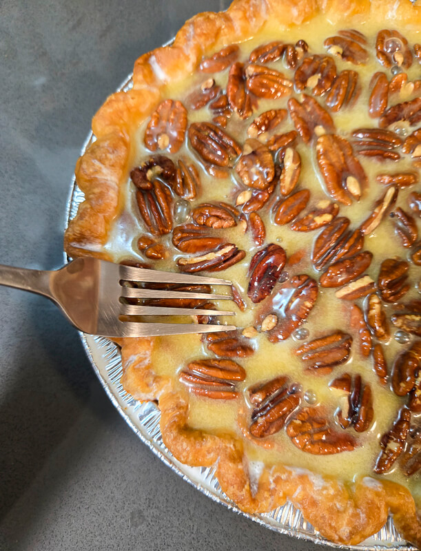 dunking pecans in pecan pie filling with a fork so they don't burn