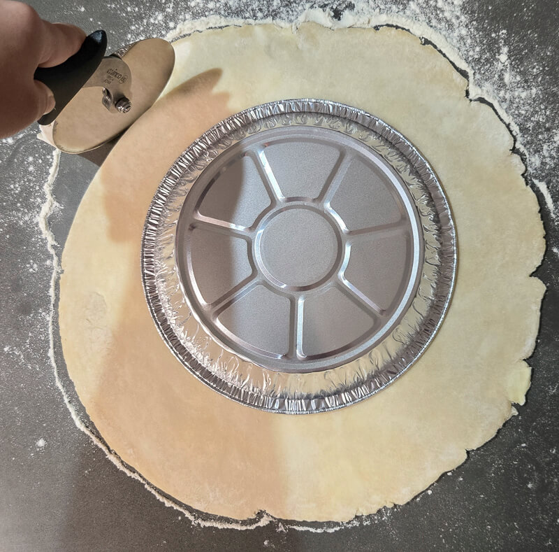 trimming rolled out pie dough using a pizza cutter