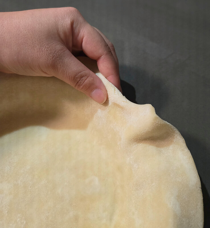rolling the edge of a pie crust for crimping
