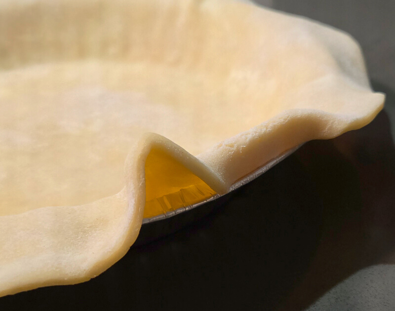 starting to roll the edge of a pie crust for crimping