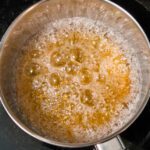a photo of a pot with boiling sugar changing color to become caramel