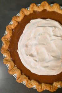 a close up, overhead photo of an apple butter pie with cinnamon whipped cream