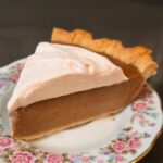 a close up square photo of a slice of apple butter pie topped with cinnamon whipped cream