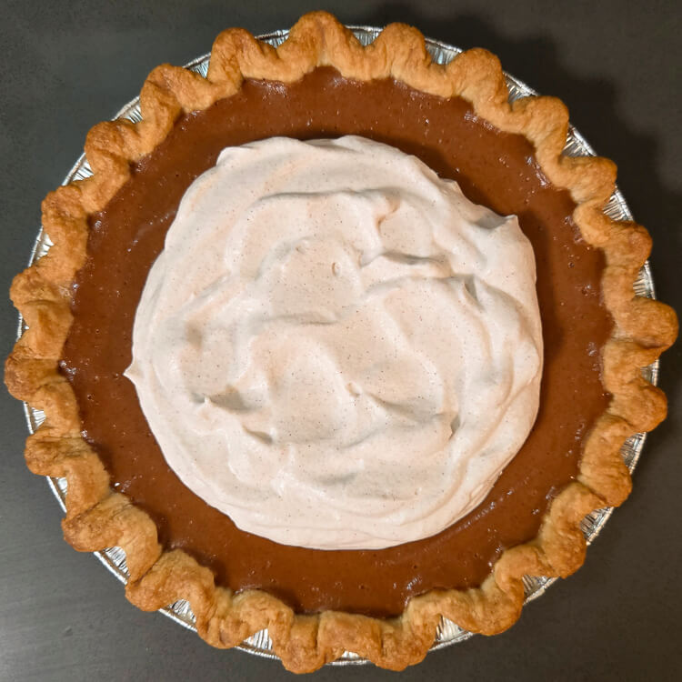 overhead photo of an apple butter pie topped with cinnamon whipped cream
