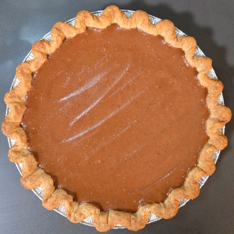 an overhead photo of an undecorated, glossy apple butter pie