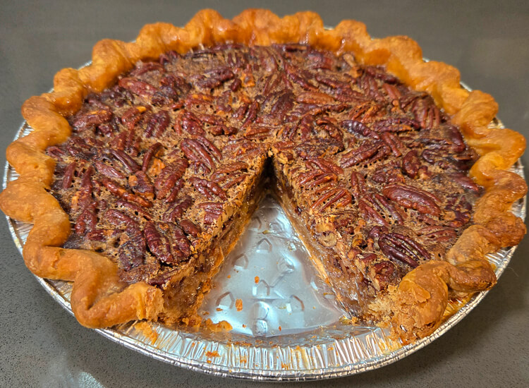 a photo of a bourbon pecan pie with a slice cut out