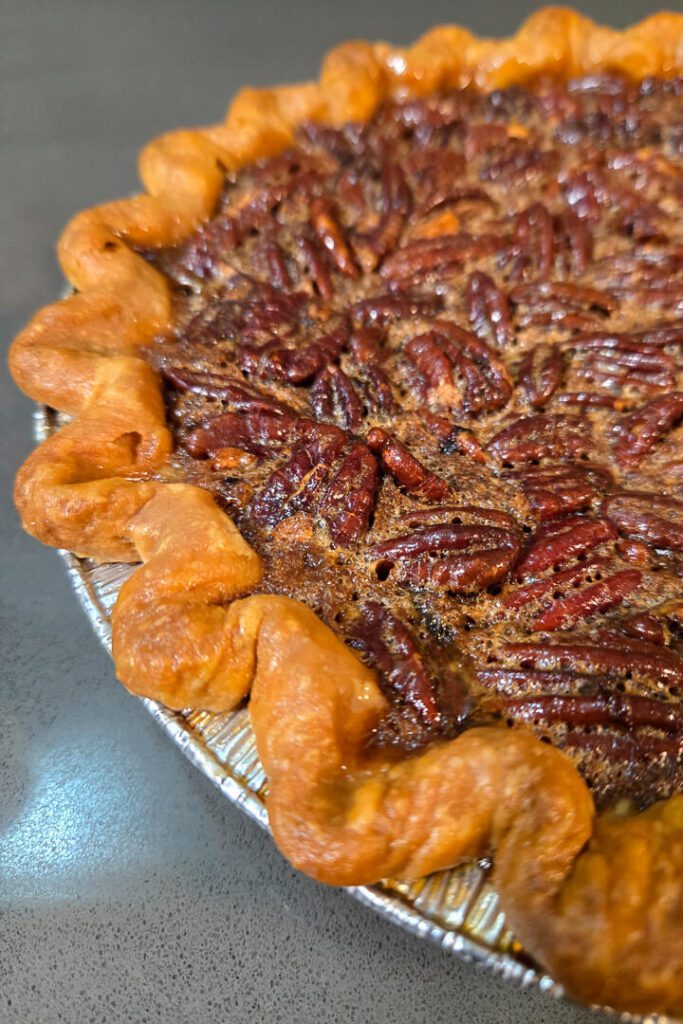 close up photo of a baked bourbon pecan pie with a golden buttery crust and caramelized pecans