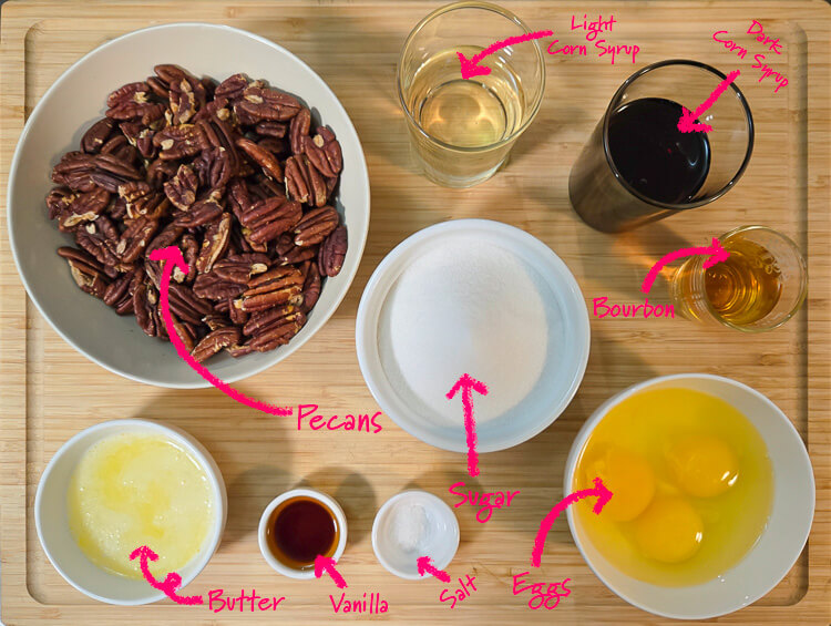 ingredients for bourbon pecan pie with labels: pecans, light corn syrup, dark corn syrup, bourbon, sugar, eggs, salt, vanilla, melted butter