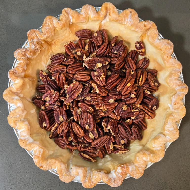 toasted pecans in a prebaked pie shell for pecan pie