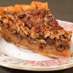 a photo of a slice of bourbon pecan pie on a floral plate