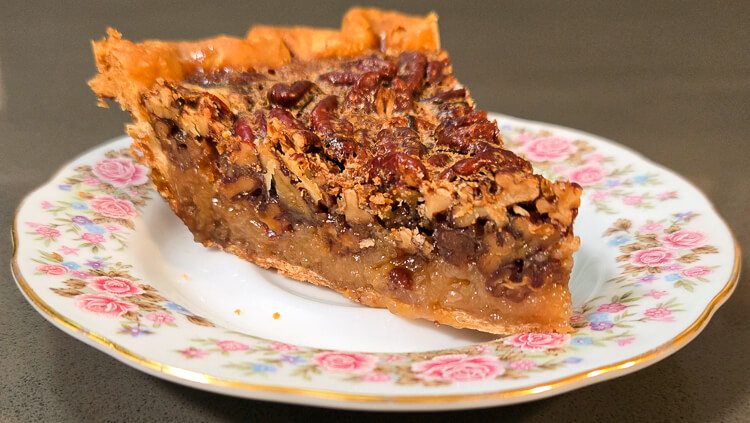 a photo of a slice of bourbon pecan pie on a floral plate