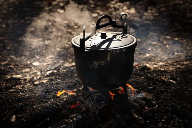 a stock image of a cast iron dutch oven over a campfire
