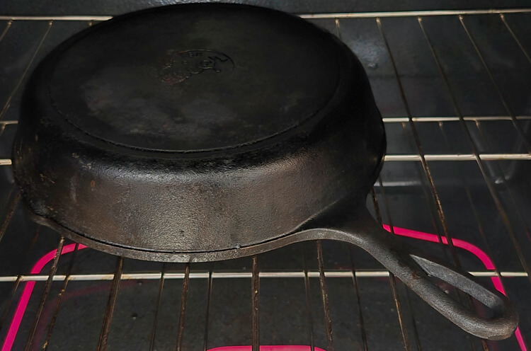 cast iron pan being seasoned in an oven upside down