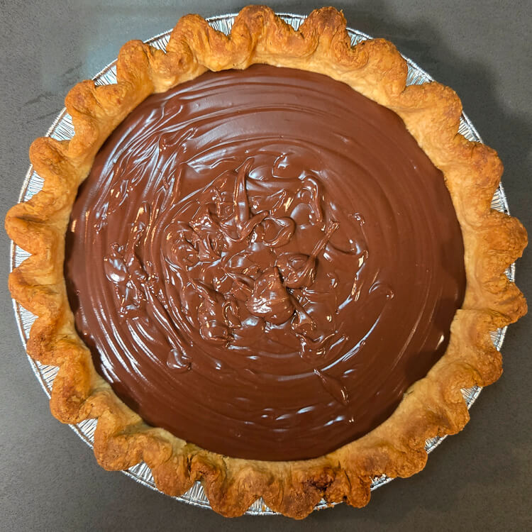 chocolate cream pie with no topping showing glossy chocolate pudding inside of a pie crust