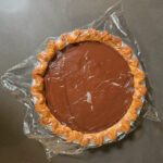 photo showing plastic wrap pressed over the top of freshly made chocolate pudding so it doesn't develop a skin as it cools