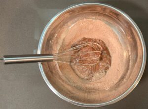 an egg slightly beaten with dry ingredients for chocolate pudding to prepare for tempering