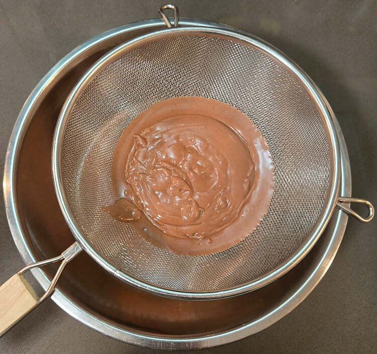 straining chocolate pudding through a fine mesh sieve to take out any clumps