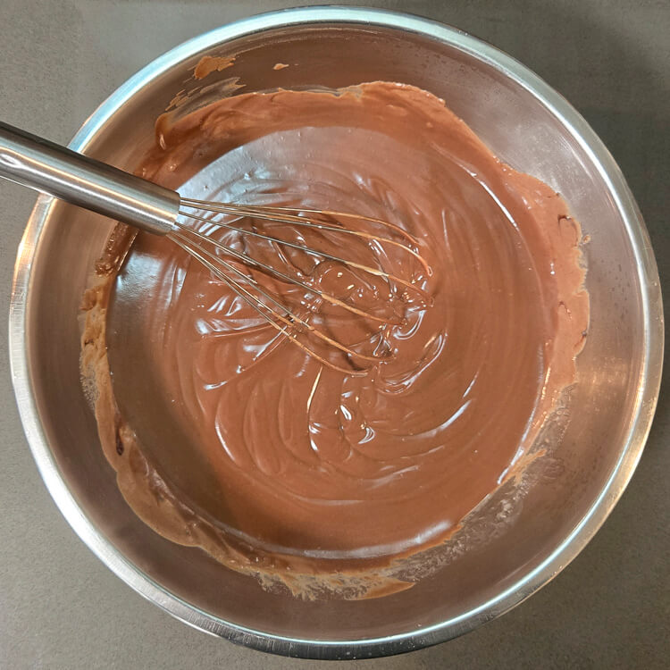 freshly made chocolate pudding in a mixing bowl with a whisk