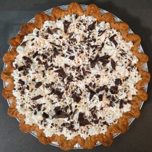 overhead photo of a decorated chocolate cream pie with piped whipped cream and chocolate shavings in a pie crust
