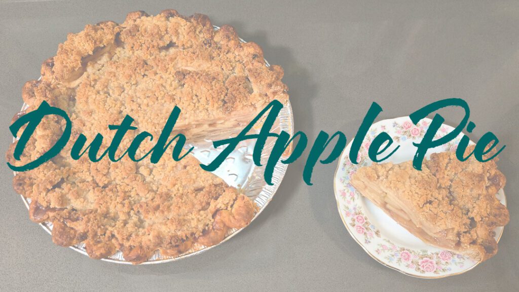 Overhead view of a Dutch apple pie with a golden crumble topping, one slice removed and served on a floral plate beside the pie with text overlay that reads "Dutch Apple Pie"