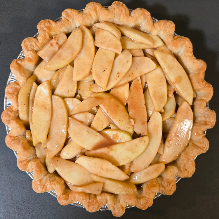 overhead photo of a dutch apple pie with no crumble topping: apple pie filling in a blind baked pie shell