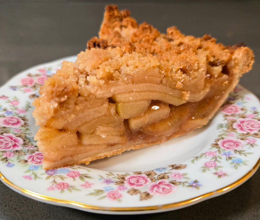 close up photo of a slice of Dutch apple pie on a floral plate