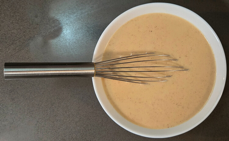 an overhead photo of a bowl of turkey gravy with a metal whisk