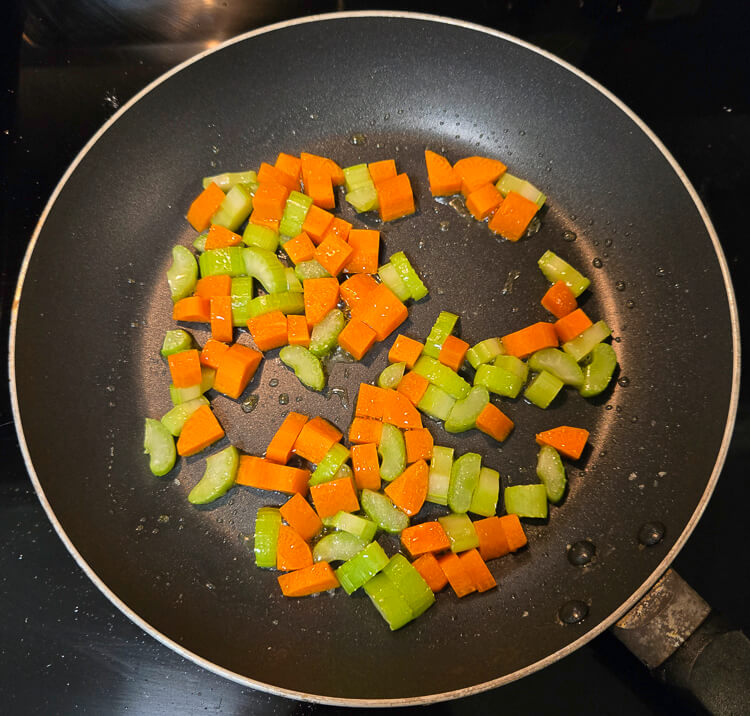 diced carrots and celery sauteed in a pan